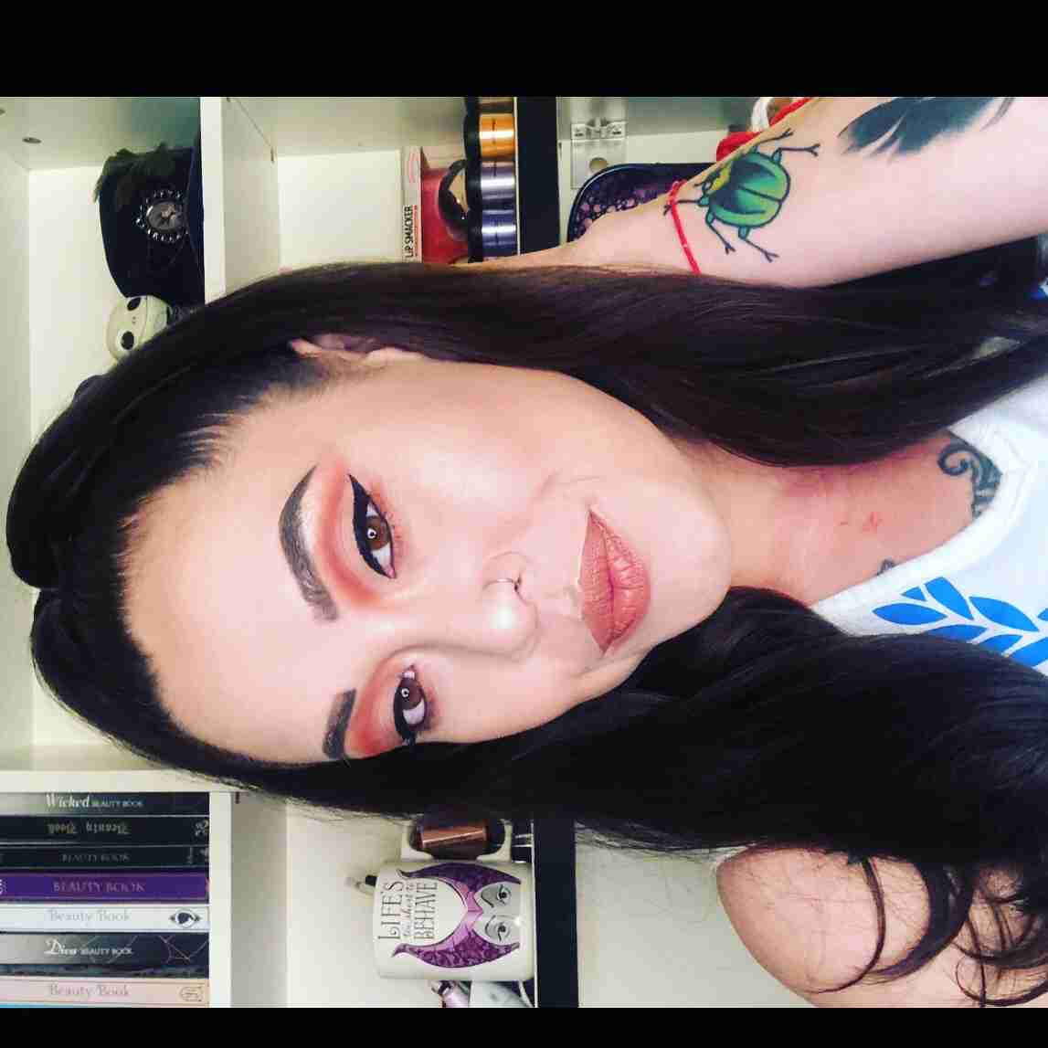Rose Eden's headshot, a biracial dark brunette with east asian features and a fred perry tank top. photo is turned sideways