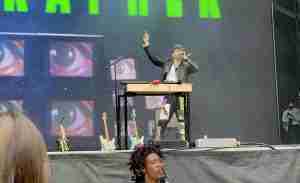 the artist singing a high note onstage w/one arm dramatically raised